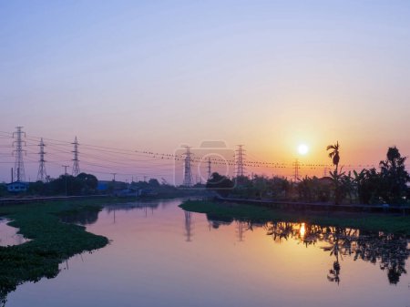 Photo for Wide angle scenic of twilight sky with  electricity transmission tower and reflection on water in river - Royalty Free Image