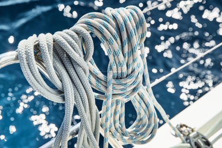 Foto de Vista de cerca de las cuerdas de velero en el clima soleado, poleas y cuerdas en el mástil, Deportes náuticos, equipo de barco, el mar está en el fondo - Imagen libre de derechos
