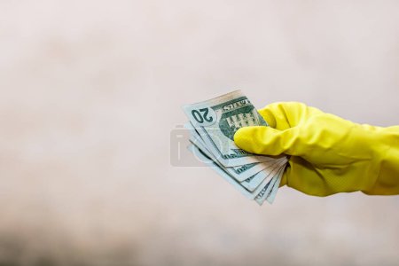 Foto de "Concepto de dinero mundial, mano con guantes recibiendo, regalando o sosteniendo billetes de 20 USD, aislados sobre fondo borroso. Brote de virus Corona COVID-19. Concepto de propagación del virus de prevención" - Imagen libre de derechos
