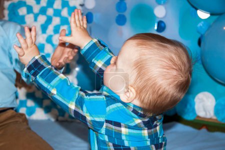 Foto de Un hermoso bebé está celebrando su primer cumpleaños. Retrato del bebé. Un niño con una camisa azul entre globos y regalos. - Imagen libre de derechos