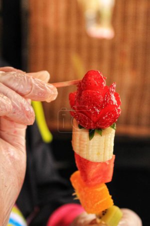 Photo for Cook hands with gloves preparing fruit skewers - Royalty Free Image
