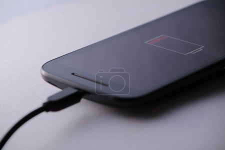 Photo for "Smartphone charging battery with micro usb cable" - Royalty Free Image