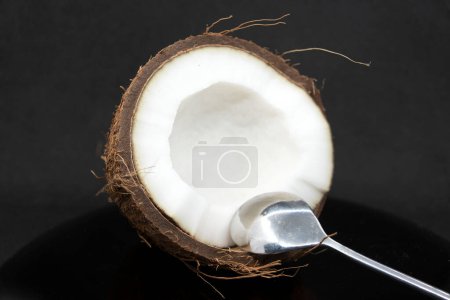 Photo for "Half coconut with pulp and dessert spoon on gray background" - Royalty Free Image