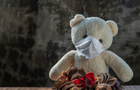 Téléchargez les photos : Ours en peluche blanc dans des masques médicaux de protection avec un vieux fond de mur de ciment. - en image libre de droit