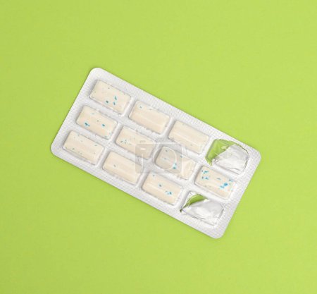 Téléchargez les photos : "rectangular pieces of gum in a blister pack on a green background" - en image libre de droit