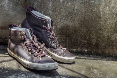 Foto de "Brown Retro High Top Canvas Sneakers se colocó en el suelo de cemento viejo. Vintage zapatillas de deporte gastadas por edad zapatos de lona marrón." - Imagen libre de derechos