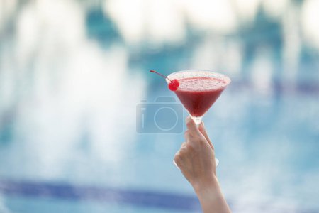 Téléchargez les photos : "Main de femme tenant un verre de cocktail au bord de la piscine." - en image libre de droit