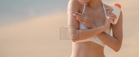 Foto de Mujer aplicando protector solar en su cuerpo en la playa. - Imagen libre de derechos