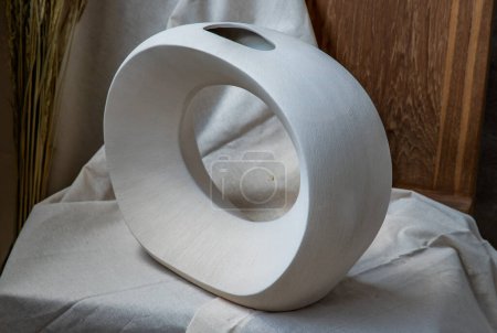 Téléchargez les photos : Beau vase blanc en céramique fait main sur chaise en bois. - en image libre de droit