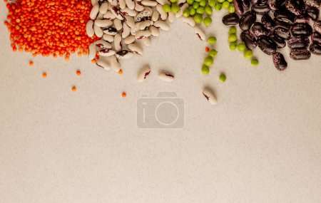 Téléchargez les photos : "A set of different dried legumes is in glass cups and is a little scattered: red lentils, green peas, red beans, white beans. Legumes at the top of the frame and copy space." - en image libre de droit