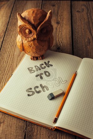 Photo for "Back to school, the concept of parenting. Owl on a wooden table. The inscription on the slate color chalk. School supplies, rustic." - Royalty Free Image