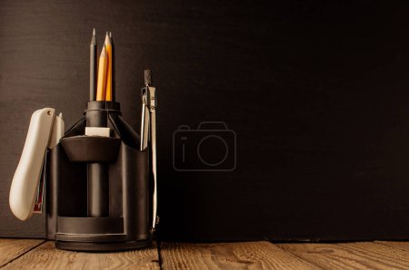 Photo for "Back to school, the concept of parenting. An assortment of consumables, stands for pens and pencils, an eraser, stationery knives, compasses.Education concept.Copy space. Rustic and vintage toning." - Royalty Free Image