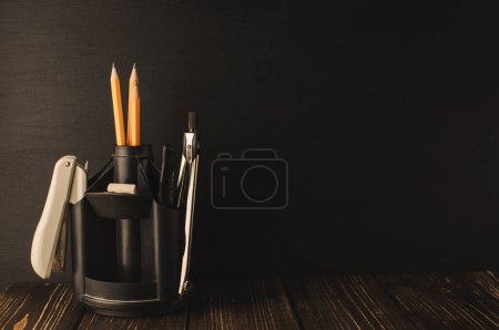 Photo for "Back to school, the concept of parenting. An assortment of consumables, stands for pens and pencils, an eraser, stationery knives, compasses.Education concept.Copy space. Rustic and vintage toning." - Royalty Free Image