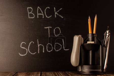 Photo for Back to school, the concept of parenting. The inscription on the blackboard with white chalk, next to it is a stand for pens with stationery. Place for text. Copy space - Royalty Free Image