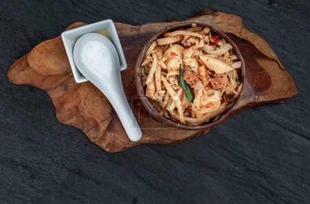 Téléchargez les photos : "Nourriture thaïlandaise, pousses de bambou frites épicées avec boule de poisson dans un bol en bois." - en image libre de droit