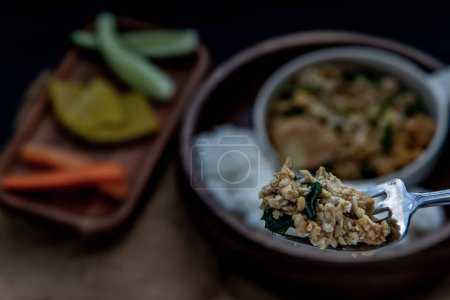 Foto de "The hand is using a fork to scoop Stir fried egg tofu with spring onion with Herbs vegetables served with steamed rice in wooden bowl." - Imagen libre de derechos