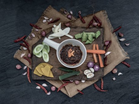 Photo for "Fried chili paste with shrimps (thai language nam prik pao) with the ingredient and fresh vegetables on wood background." - Royalty Free Image