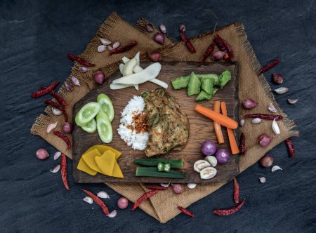 Photo for "A local Thai food style, Fried acacia pennata omelet or cha-om eggs on jasmine rice with the ingredient and fresh vegetables on a wooden background, Thai Cuisine." - Royalty Free Image