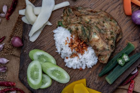 Photo for "A local Thai food style, Fried acacia pennata omelet or cha-om eggs on jasmine rice with the ingredient and fresh vegetables on a wooden background, Thai Cuisine." - Royalty Free Image