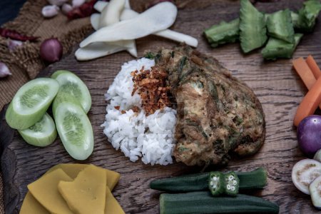 Foto de "A local Thai food style, Fried acacia pennata omelet or cha-om eggs on jasmine rice with the ingredient and fresh vegetables on a wooden background, Thai Cuisine." - Imagen libre de derechos