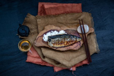Photo for "Japanese meal for dinner saba fish grilled on rice with teriyaki sauce on a wooden background served with hot tea. Japanese style." - Royalty Free Image