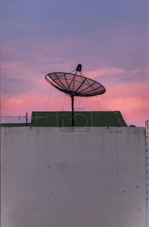 Téléchargez les photos : Récepteur d'antenne de plat satellite noir sur fond de ciel bleu. - en image libre de droit