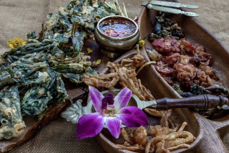 Foto de "Flores crujientes, hierbas crujientes y verduras crujientes servidas con salsa dulce en una bandeja de madera." - Imagen libre de derechos