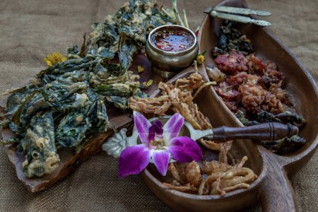 Foto de "Flores crujientes, hierbas crujientes y verduras crujientes servidas con salsa dulce en una bandeja de madera." - Imagen libre de derechos