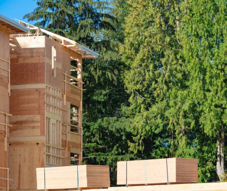 Foto de "Edificio de apartamentos en construcción con dos troncos de madera almacenados en un lado
" - Imagen libre de derechos