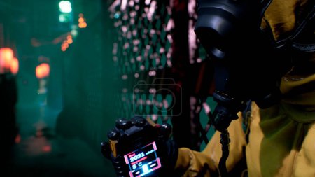 Photo for "A nuclear physicist sits on a neon street and checks the surrounding radiation with a dosimeter. Post-apocalyptic world concept. 3D Rendering." - Royalty Free Image