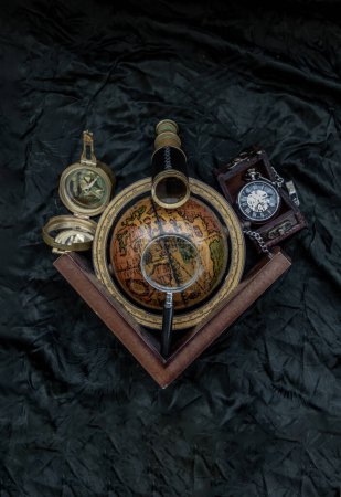 Foto de "Viajes o aventura concepto de fondo. Reloj de bolsillo, binoculares, brújula antigua, globo y lupa sobre fondo oscuro." - Imagen libre de derechos