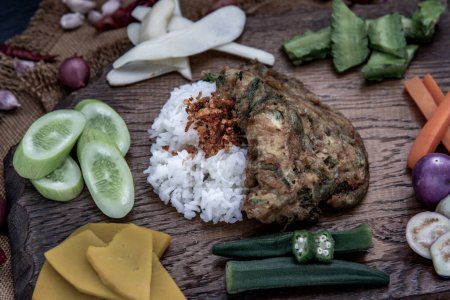 Foto de "Un estilo de comida tailandesa local, tortilla de acacia pennata frita o huevos cha-om sobre arroz jazmín con el ingrediente y verduras frescas sobre un fondo de madera, cocina tailandesa." - Imagen libre de derechos