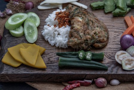 Téléchargez les photos : "Un style thaï local, omelette de pennata d'acacia frite ou œufs cha-om sur riz jasmin avec l'ingrédient et légumes frais sur un fond en bois, Cuisine thaïlandaise." - en image libre de droit