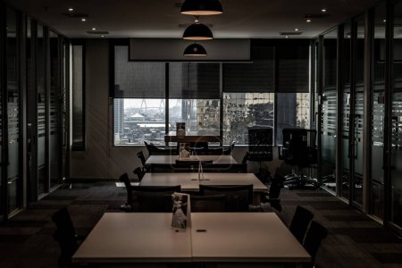 Foto de "Ambiente de interiores de oficina moderno y elegante, hay una zona de reunión con una gran mesa de madera con sillas grises y tabiques de vidrio." - Imagen libre de derechos