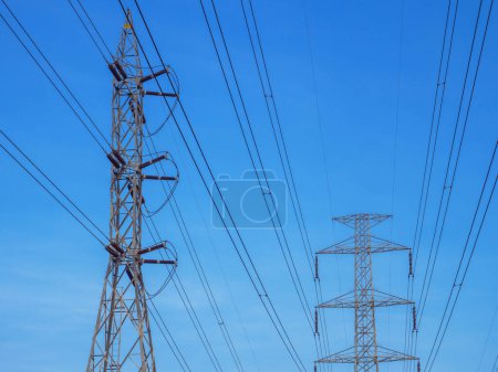 Foto de Parte superior de torres de transmisión de alto voltaje con línea eléctrica sobre cielo azul y fondo de nube blanca - Imagen libre de derechos
