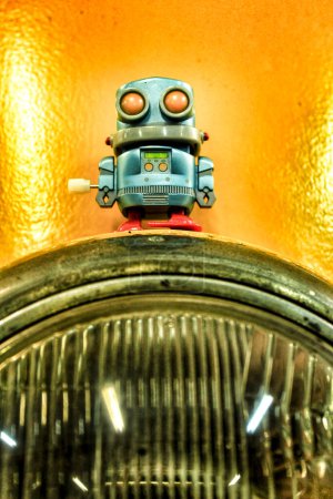 Téléchargez les photos : "Toy robot on front vintage light of car" - en image libre de droit