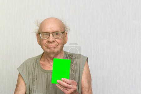 Téléchargez les photos : Vieil homme chauve à la retraite avec des lunettes en chemise grise est vide dans sa main. - en image libre de droit