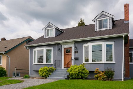 Téléchargez les photos : Maison résidentielle moyenne avec pelouse verte par temps nuageux au Canada - en image libre de droit