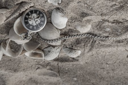 Foto de Reloj de bolsillo antiguo y conchas en arena en la playa. Al revés.. - Imagen libre de derechos