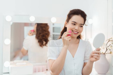Téléchargez les photos : Belle femme asiatique utilisant une éponge de maquillage, poudre pressée pour le visage de peau lisse - en image libre de droit