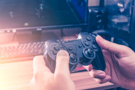 Téléchargez les photos : Game joystick in the hands of a teenager playing on the console - en image libre de droit