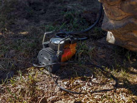 Photo for Electric compressor with gauge on ground next to tractor wheel - Royalty Free Image