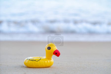 Foto de Yellow rubber duck on the seashore in the morning, sand beach. - Imagen libre de derechos
