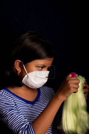 Photo for Little girl with medical face mask, playing with her doll - Royalty Free Image