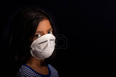 Téléchargez les photos : Portrait de petite fille portant un masque médical utilisé pour la protection contre le virus - en image libre de droit