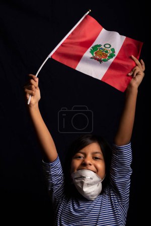 Foto de Retrato de niña peruana usando máscara médica y sosteniendo con suerte la bandera de Perú - Imagen libre de derechos