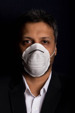 Photo for Young handsome with fear and industrial mask to prevent the spread of contagious viruses or chemical gases - Royalty Free Image
