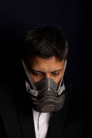 Téléchargez les photos : Jeune beau avec peur et masque industriel pour prévenir la propagation de virus contagieux ou de gaz chimiques - en image libre de droit