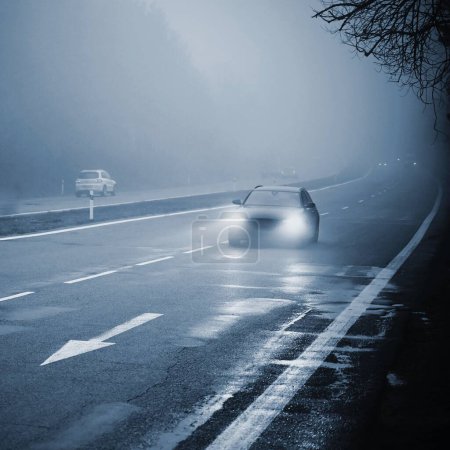 Téléchargez les photos : Des voitures dans le brouillard. Mauvais temps d'hiver et circulation automobile dangereuse sur la route. Véhicules légers en journée brumeuse
. - en image libre de droit
