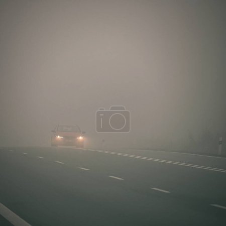 Téléchargez les photos : Conduite par mauvais temps - route de campagne brumeuse et brumeuse. Autoroute - circulation routière. Heure d'hiver. - en image libre de droit